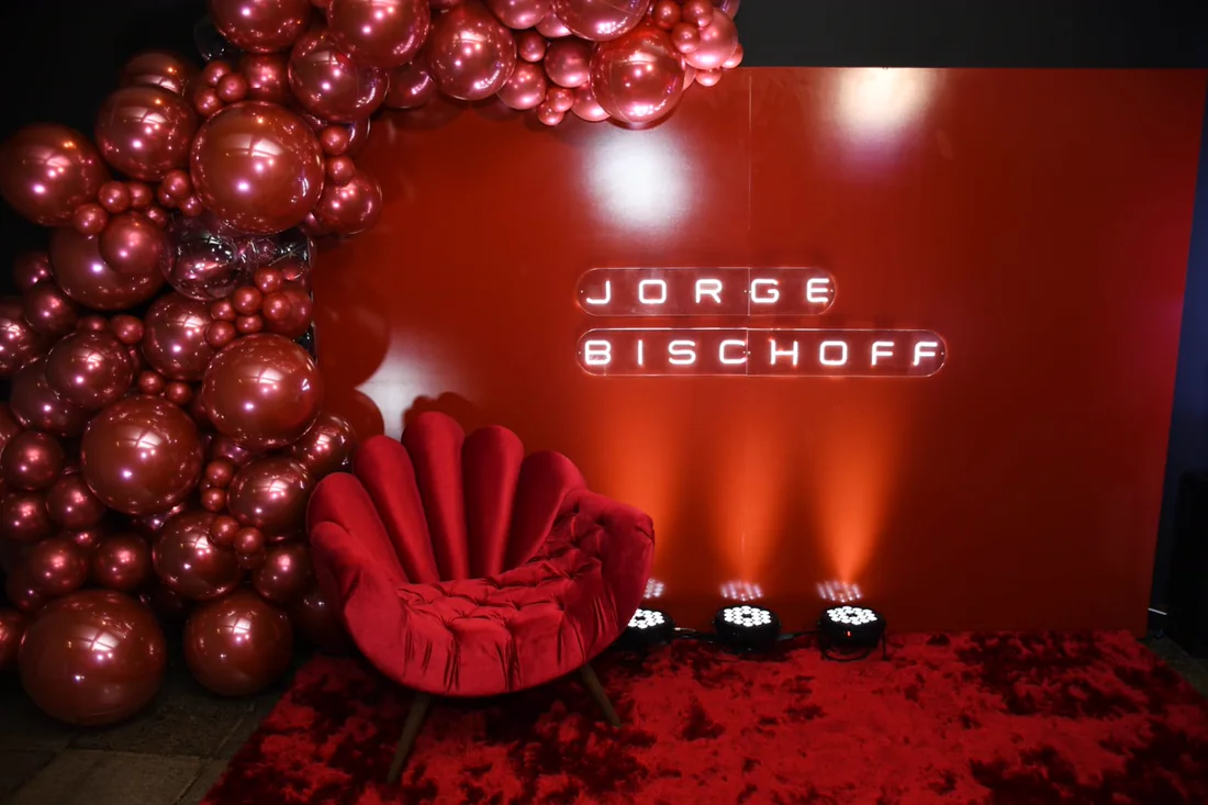 Evento da marca Jorge Bischoff, com letreiro em neon, instalação de balões e poltrona vermelha